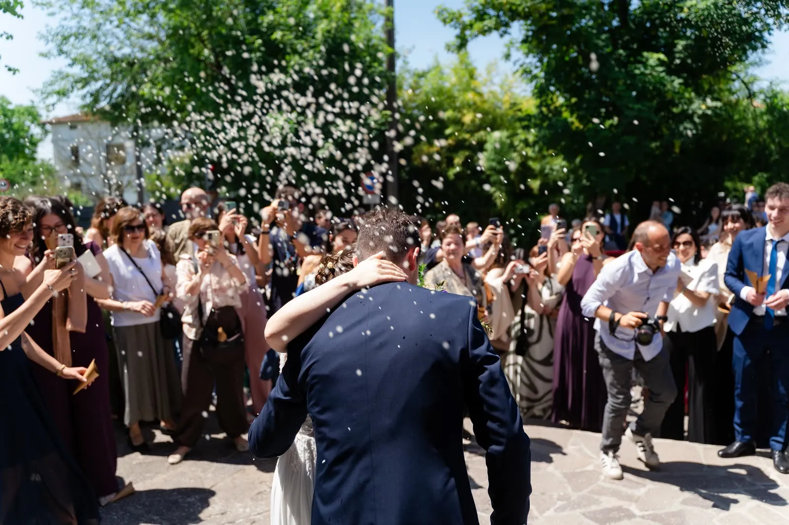 Gli sposi si abbracciano sotto una pioggia di riso, circondati dagli invitati all'uscita dalla chiesa