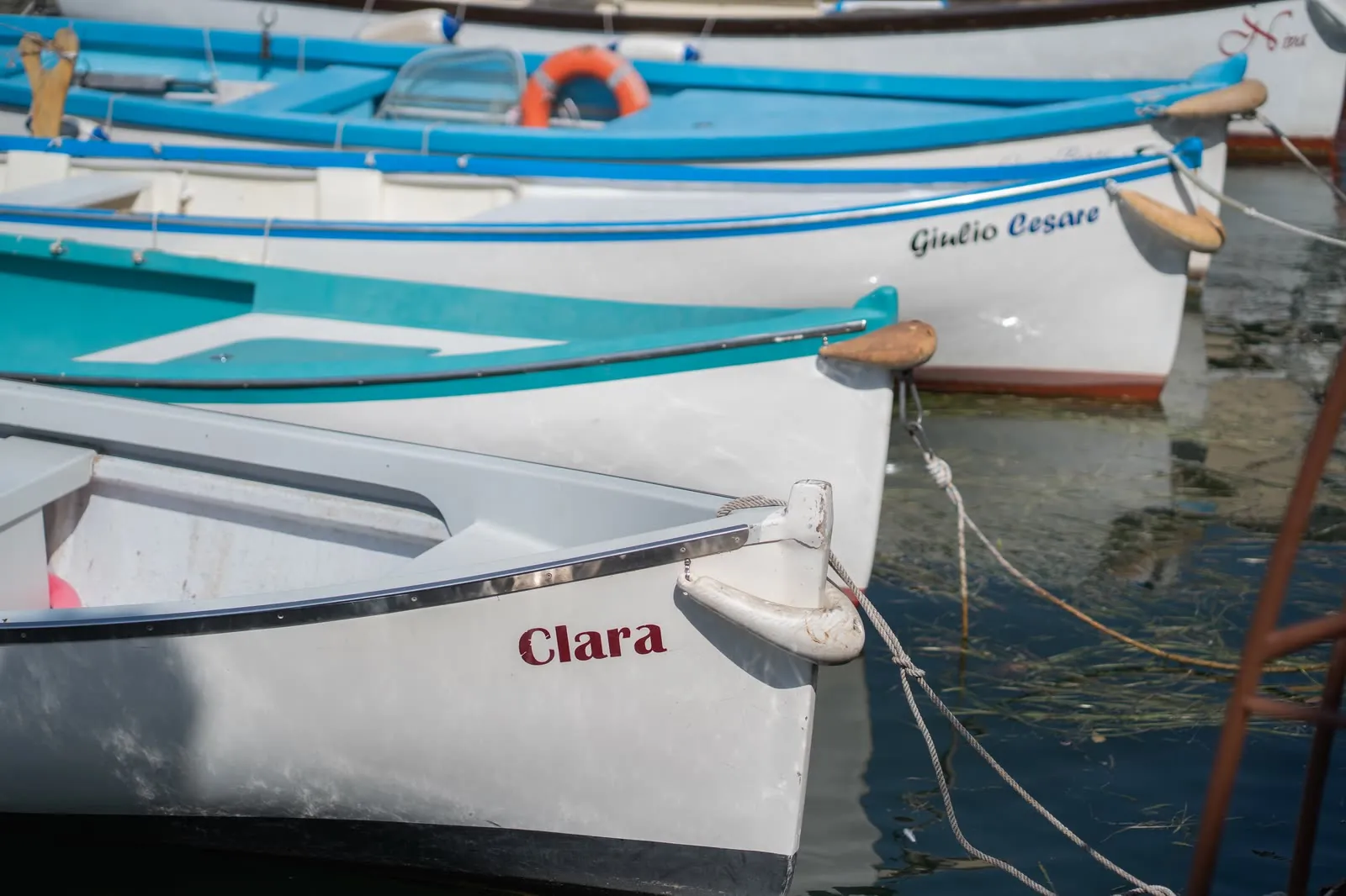 Le barche colorate ormeggiate nel porticciolo di Lazise, con i nomi dipinti a prua