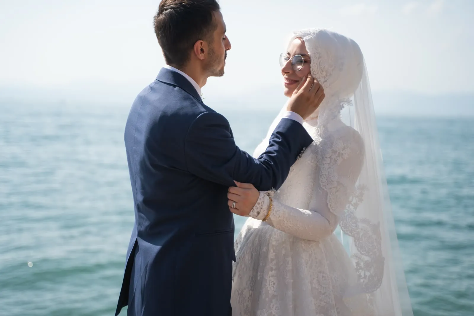 Lo sposo accarezza il viso della sposa, con il Lago di Garda alle spalle